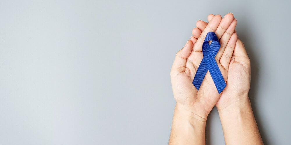 manos aguantando lazo azul cáncer rectal remisión en estudio